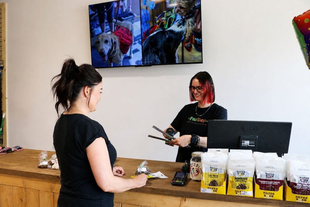 A Paw Shop team member helping a customer at the checkout counter in Cranbrook